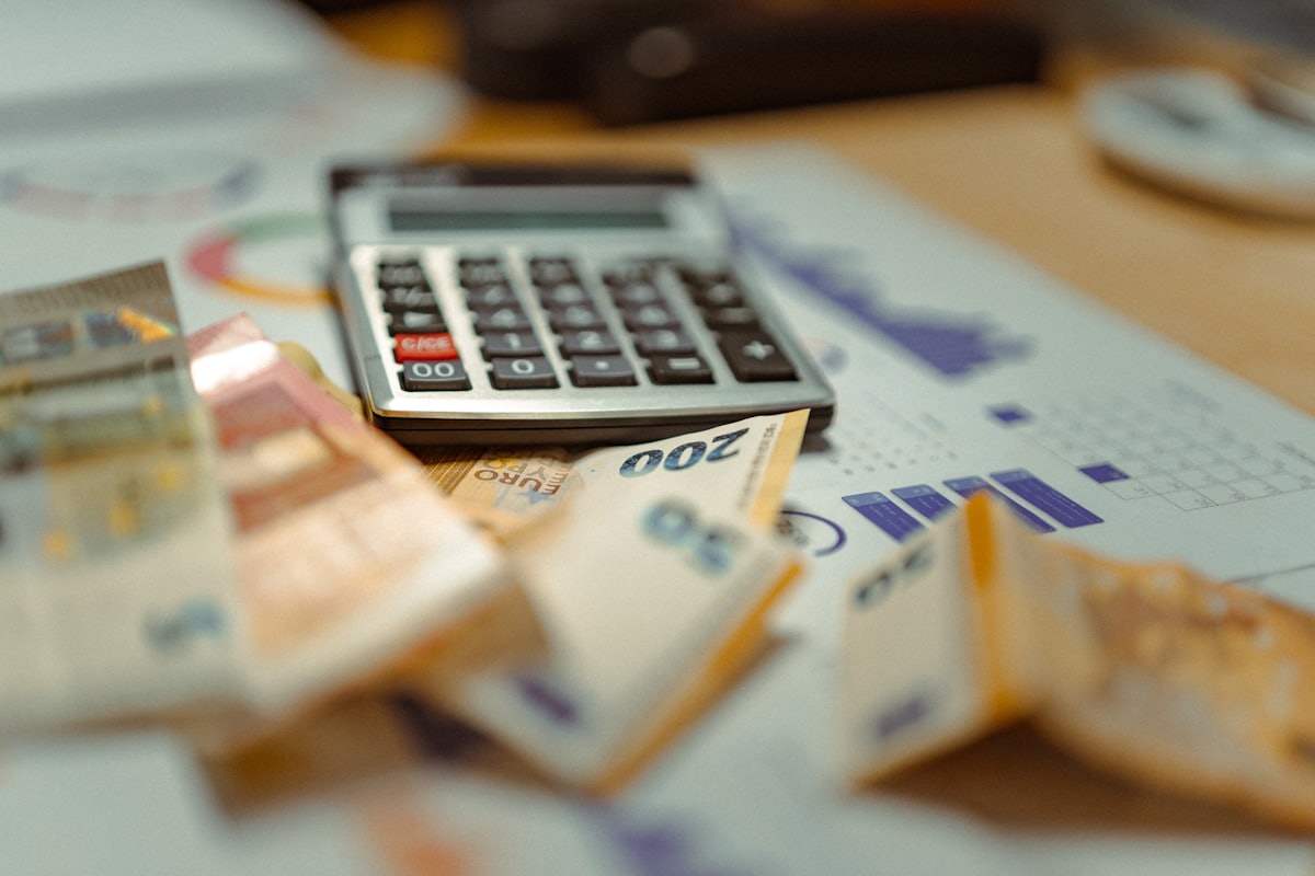 Kalkulator dan uang rupiah di atas meja — ilustrasi artikel cashback vs rollingan